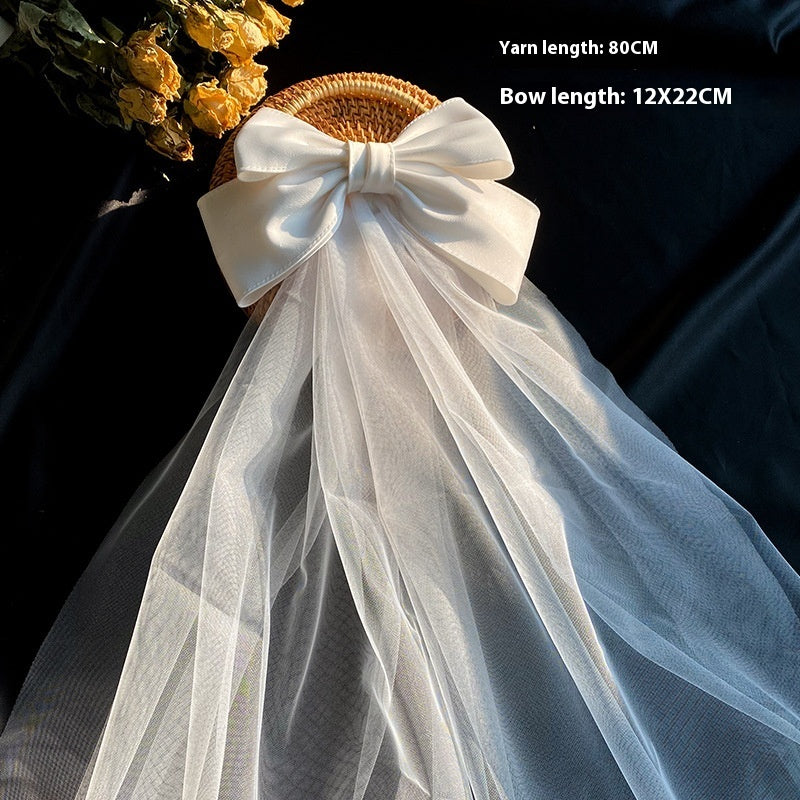 Bow Veil white satin bow with cascading sheer tulle veil on wicker display basket