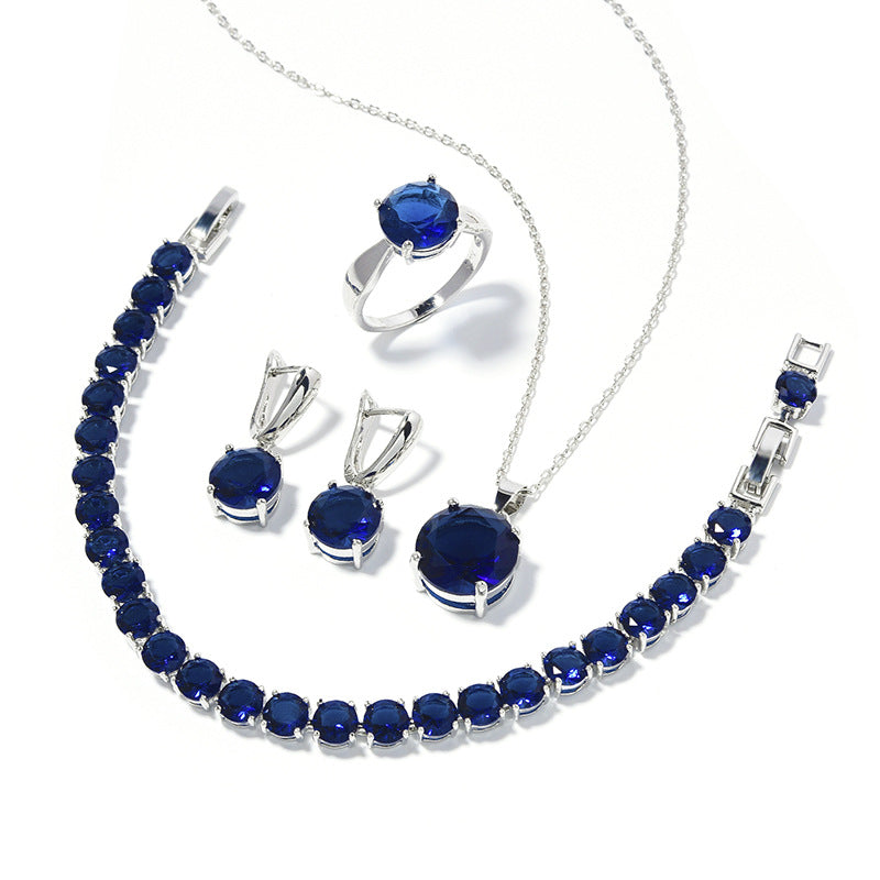 Geometric round jewelry set in silver with deep blue stones: necklace, bracelet, ring, and earrings
