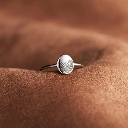 Silver ring with a wave design on a sandy surface