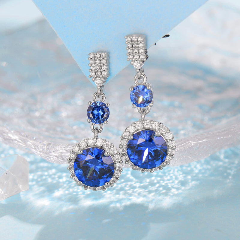 Earrings pair by cj; silver-tone drop earrings with deep blue stones and crystal halos