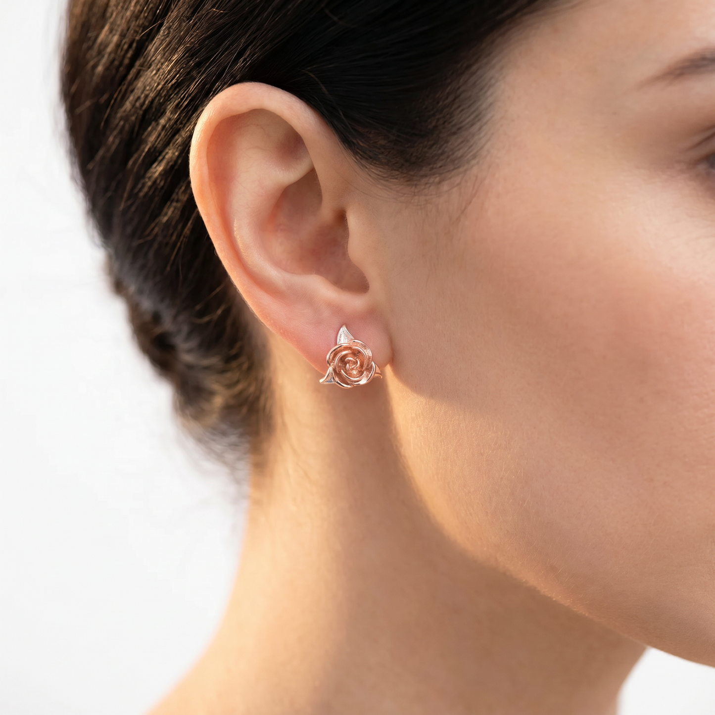 Creative jewelry rose earrings in rose gold worn on the ear.