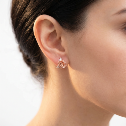 Creative jewelry rose earrings in rose gold worn on the ear.